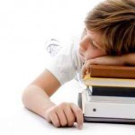 Cognitive fatigue. Boy asleep with head on a pile of books