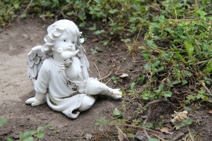 Photograph of statue of cherub angel in garden setting