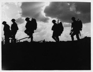 Photo of soldiers silhouetted marching with cloudy sky behind
